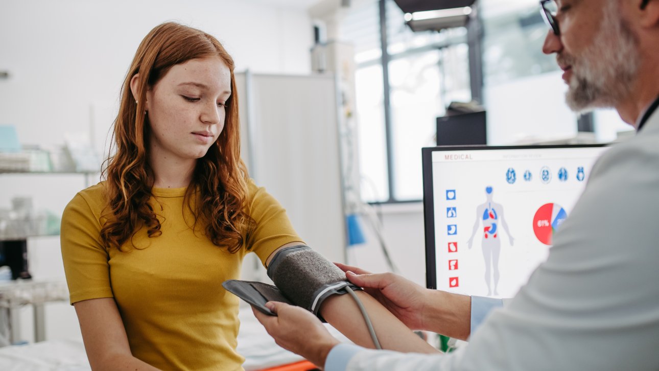  A teenage girl has her blood pressure taken by a doctor.