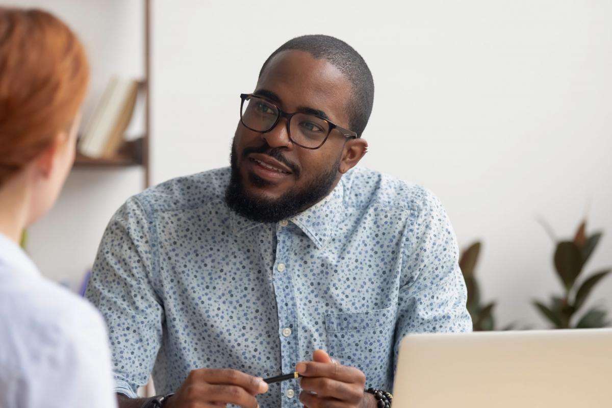 Homme souriant tenant un crayon et discutant avec une femme
