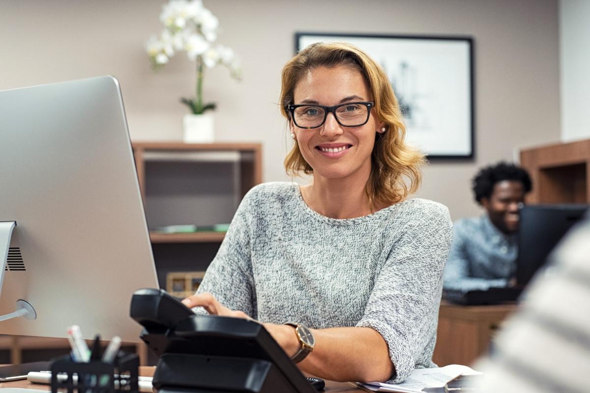Femme souriante assise devant son ordinateur de bureau