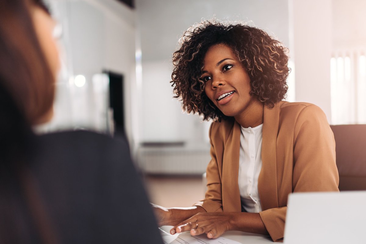 Médiatrice assise à son bureau et discutant avec une cliente ou une collègue..