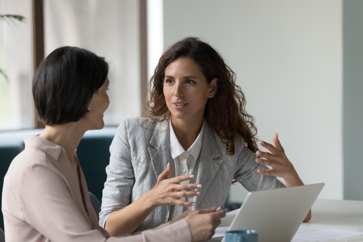 Conseillère en gestion financière discutant avec une collègue au bureau.