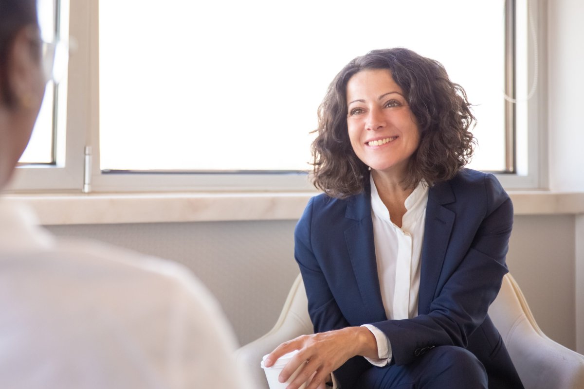 Directrice assise dans un fauteuil et souriant à un membre de son équipe assis en face d'elle.
