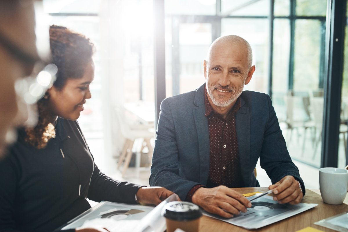 Directeur souriant à la caméra durant une rencontre avec son équipe de travail.