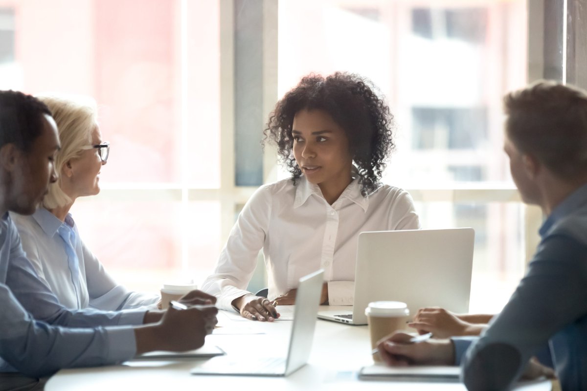 Une coordonnatrice et trois personnes de son équipe sont assis autour d'un bureau et discutent.