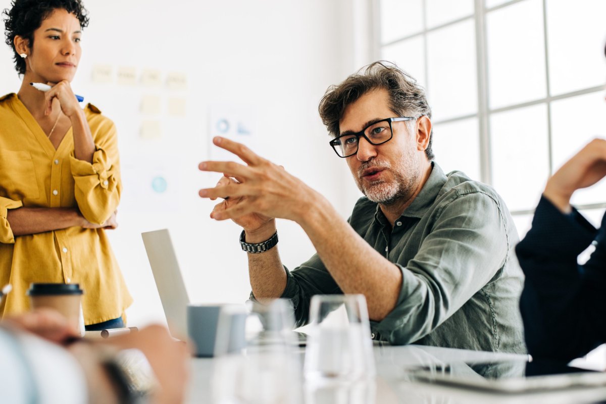 Directeur adjoint discutant avec son équipe et sa directrice autour d'un bureau.