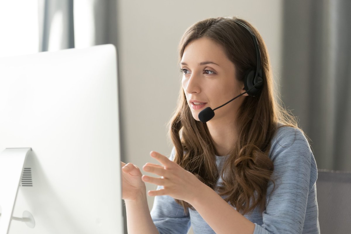 Une enquêtrice ajointe parle à un citoyen dans son micro-casque en regardant son écran d'ordinateur.