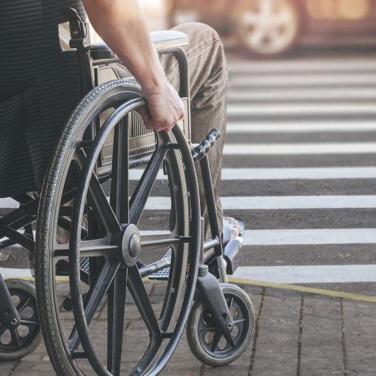 Personne en fauteuil roulant sur un trottoir de stationnement