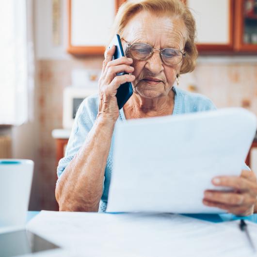 Dame âgée tenant une feuille et parlant au téléphone