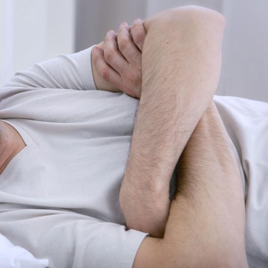 Homme grincheux allongé dans un lit avec les bras croisés