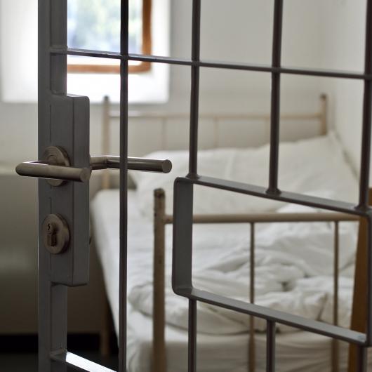 Lit vu à travers la porte à barreaux d'une cellule de prison
