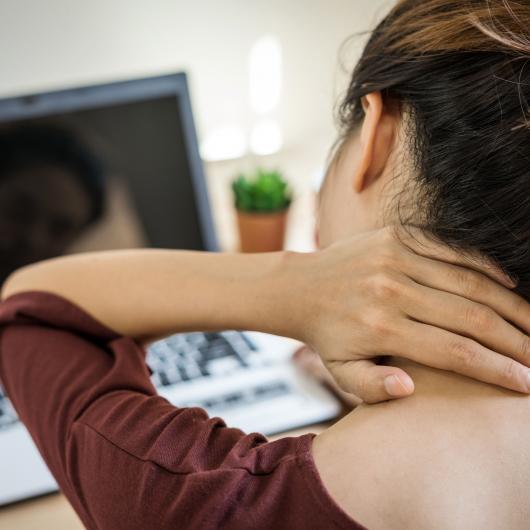 Femme regardant un ordinateur en massant son cou douloureux