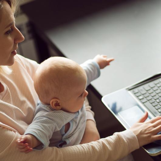 Mère travaillant à l'ordinateur en tenant son bébé