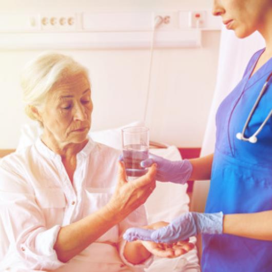 Femme regardant le verre d'eau que lui donne une infirmière