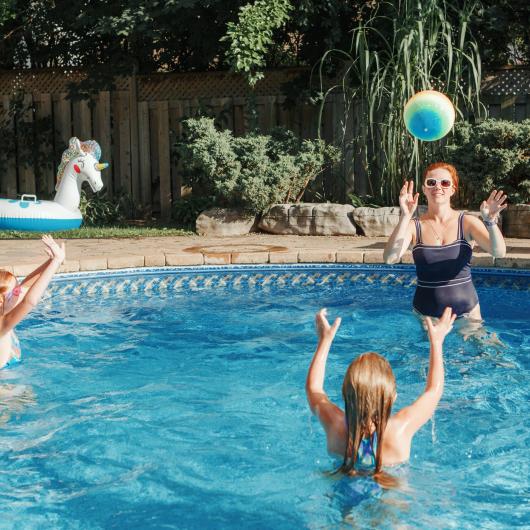 Femme jouant au ballon dans la piscine avec deux enfants