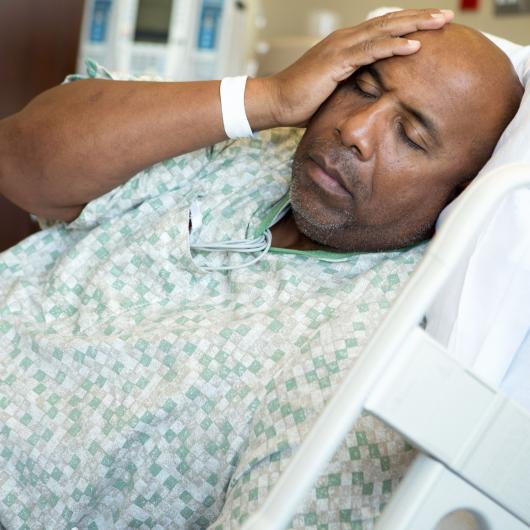 Homme se tenant la tête dans son lit d'hôpital