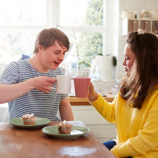 Jeune homme atteint de trisomie buvant un café avec sa mère
