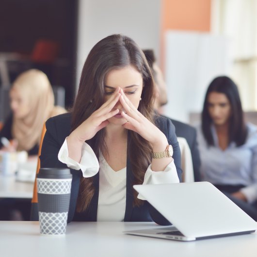Femme affichant un air triste au bureau pendant que ses collègues travaillent