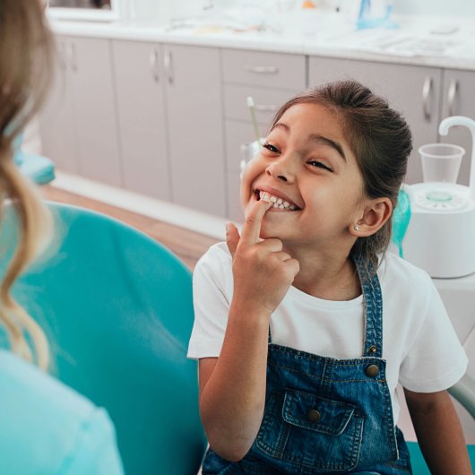 Little girl proudly showing her teeth to her dentist