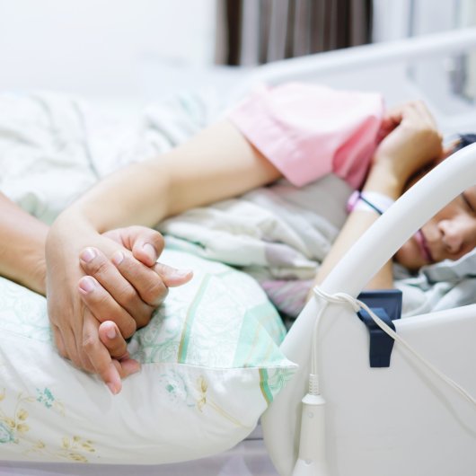 Femme allongée dans un lit d'hôpital et tenant la main de son accompagnateur