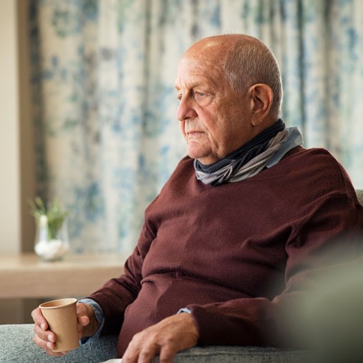 Lonely and vulnerable elderly man sitting in an armchair