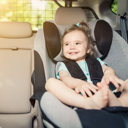 Fillette souriante assise dans un siège d'auto pour enfant