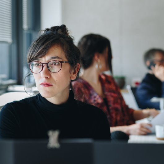 Une femme à l'ordinateur et ses collègues qui travaillent en arrière-plan