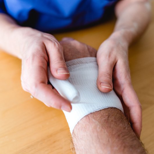 A person wrapping another person's wrist with a bandage.