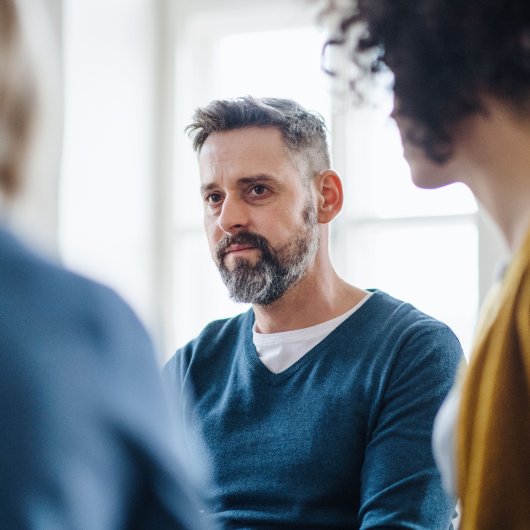 Man with tired eyes participating in group therapy.