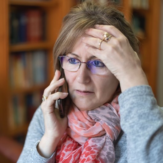 Femme inquiète posant une main sur son front en parlant au téléphone.