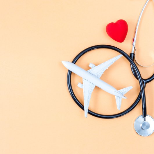 Tiny plane placed near a stethoscope and a small red heart.
