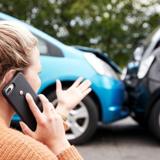 Victime d'un accident de la route parlant au cellulaire en regardant sa voiture qui est entrée en collision avec un autre véhicule.