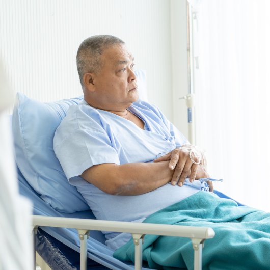 Un homme allongé dans son lit d'hôpital affiche un air mécontent.