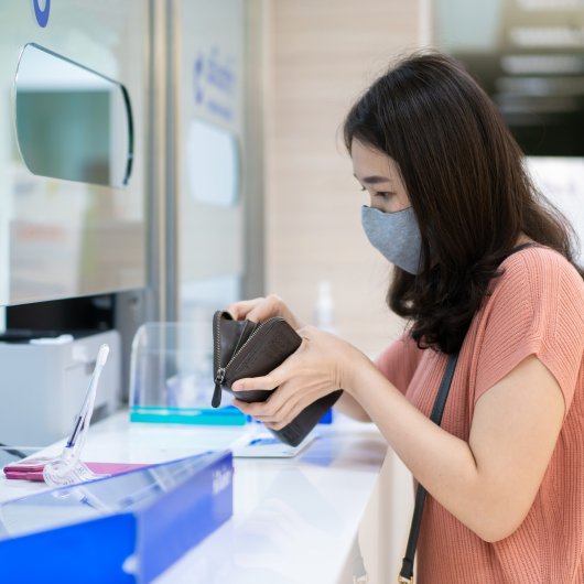 Femme cherchant une carte dans son portefeuille devant le comptoir de la réception de l'hôpital.