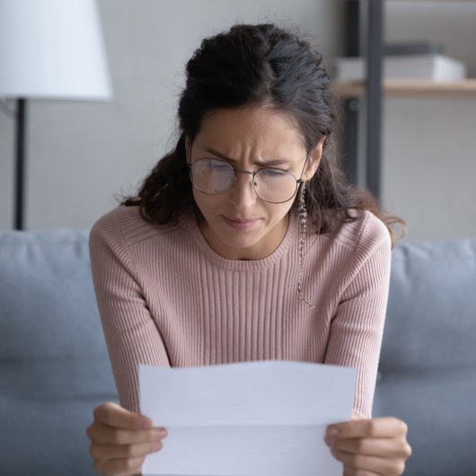 Femme assise sur son divan et lisant une lettre.