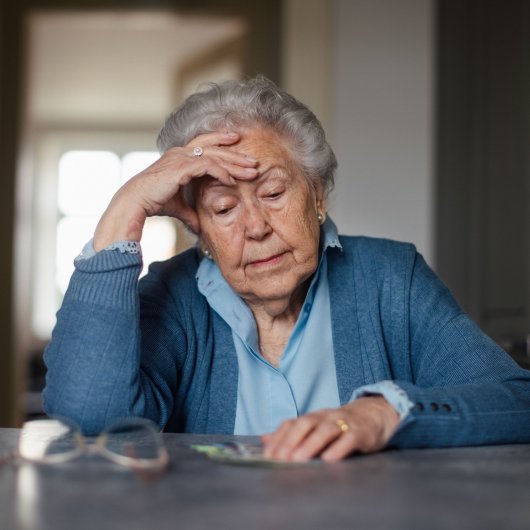 Une dame âgée regarde son argent posé sur une table en affichant un air découragé.