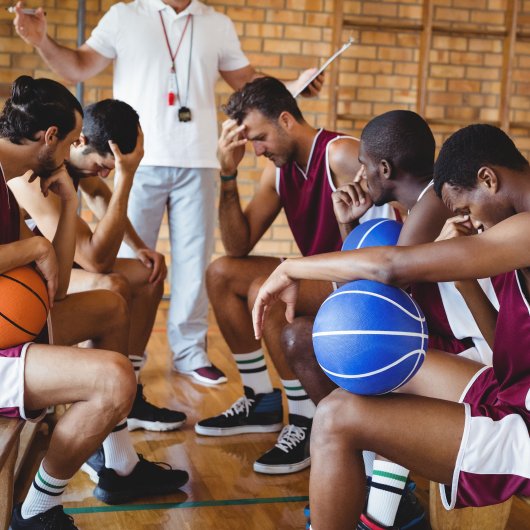 A coach talks to basketball players who look sad.