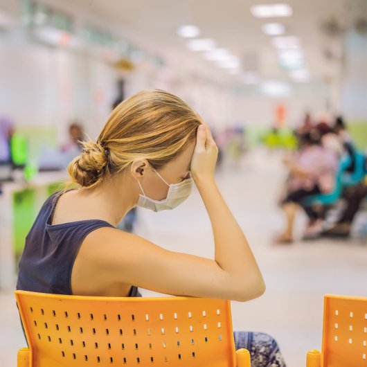Woman waiting on a chair in a hospital waiting room.