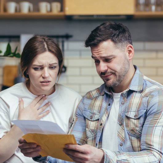 Couple lisant une lettre en affichant un air étonné et triste.