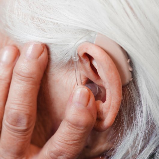 A close-up of a woman’s ear wearing a hearing aid designed for her hearing loss.