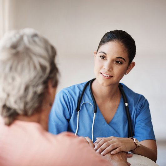 Une infirmière praticienne spécialisée parle avec une patiente.